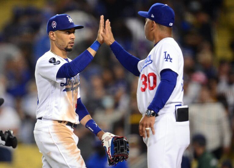 Los Angeles Dodgers right fielder Mookie Betts (50) and manager Dave Roberts (30) celebrate the 5-4 victory against the San Diego Padres at Dodger Stadium.