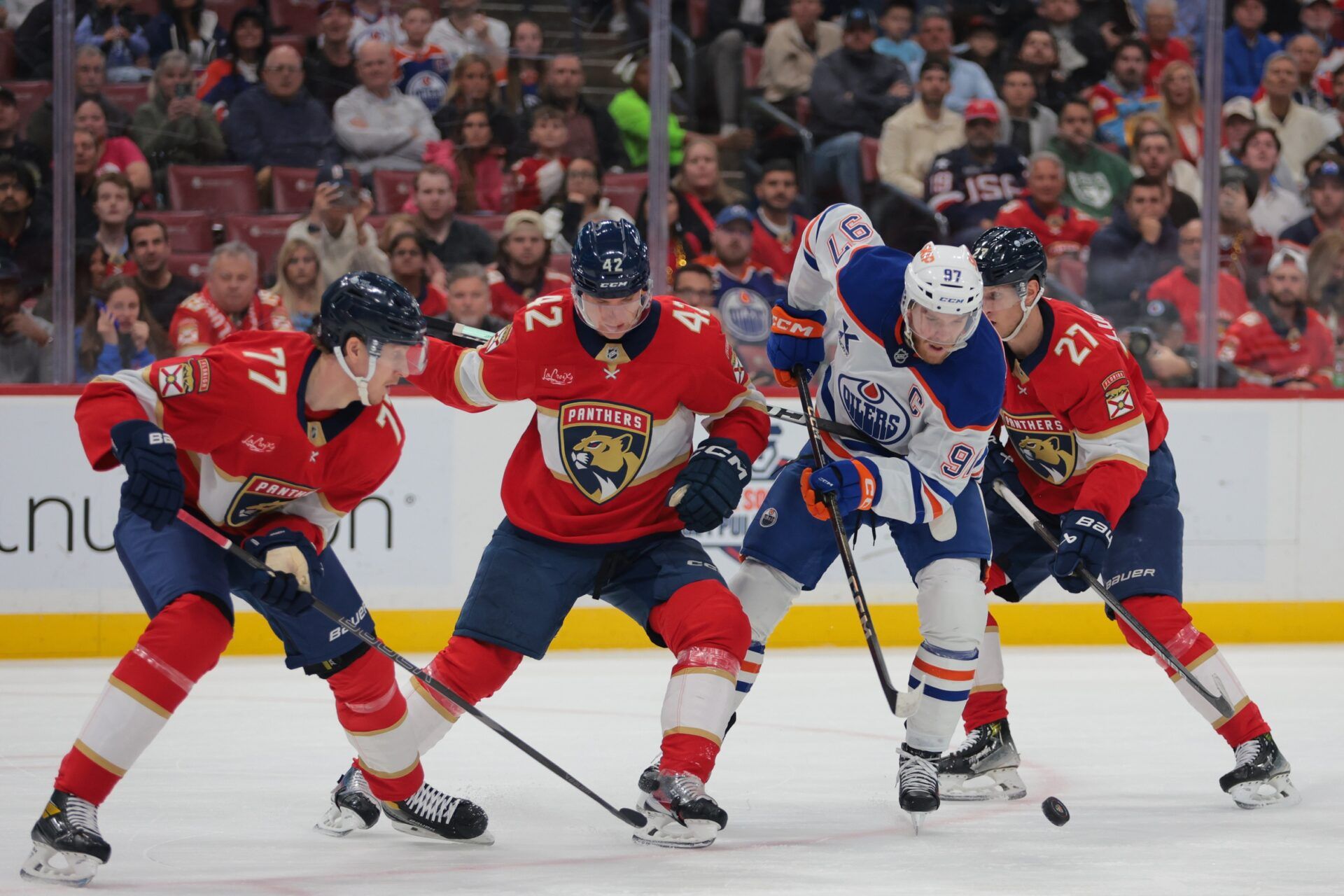 Edmonton Oilers center Connor McDavid (97) protects the puck from Florida Panthers defenseman Niko Mikkola (77), defenseman Gustav Forsling (42) and center Eetu Luostarinen (27) during the first period at Amerant Bank Arena.