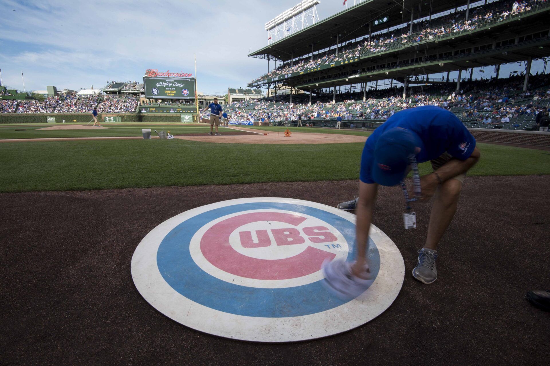 A member of the grounds crew wipes off the Chicago Cubs' on deck logo prior to a game against the San Diego Padres at Wrigley Field.
