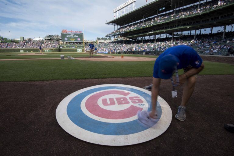 A member of the grounds crew wipes off the Chicago Cubs' on deck logo prior to a game against the San Diego Padres at Wrigley Field.