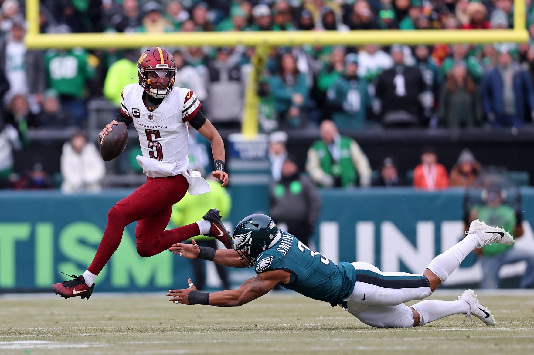 Washington Commanders quarterback Jayden Daniels (5) leaps to avoid the tackle of Philadelphia Eagles linebacker Nolan Smith Jr. (3) during the first half of the NFC Championship game at Lincoln Financial Field.