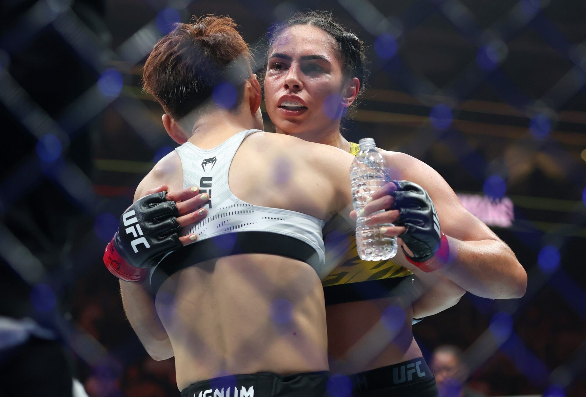 Ariane Da Silva (red gloves) hugs Wang Cong (blue gloves) after their fight during UFC 316 at Prudential Center.