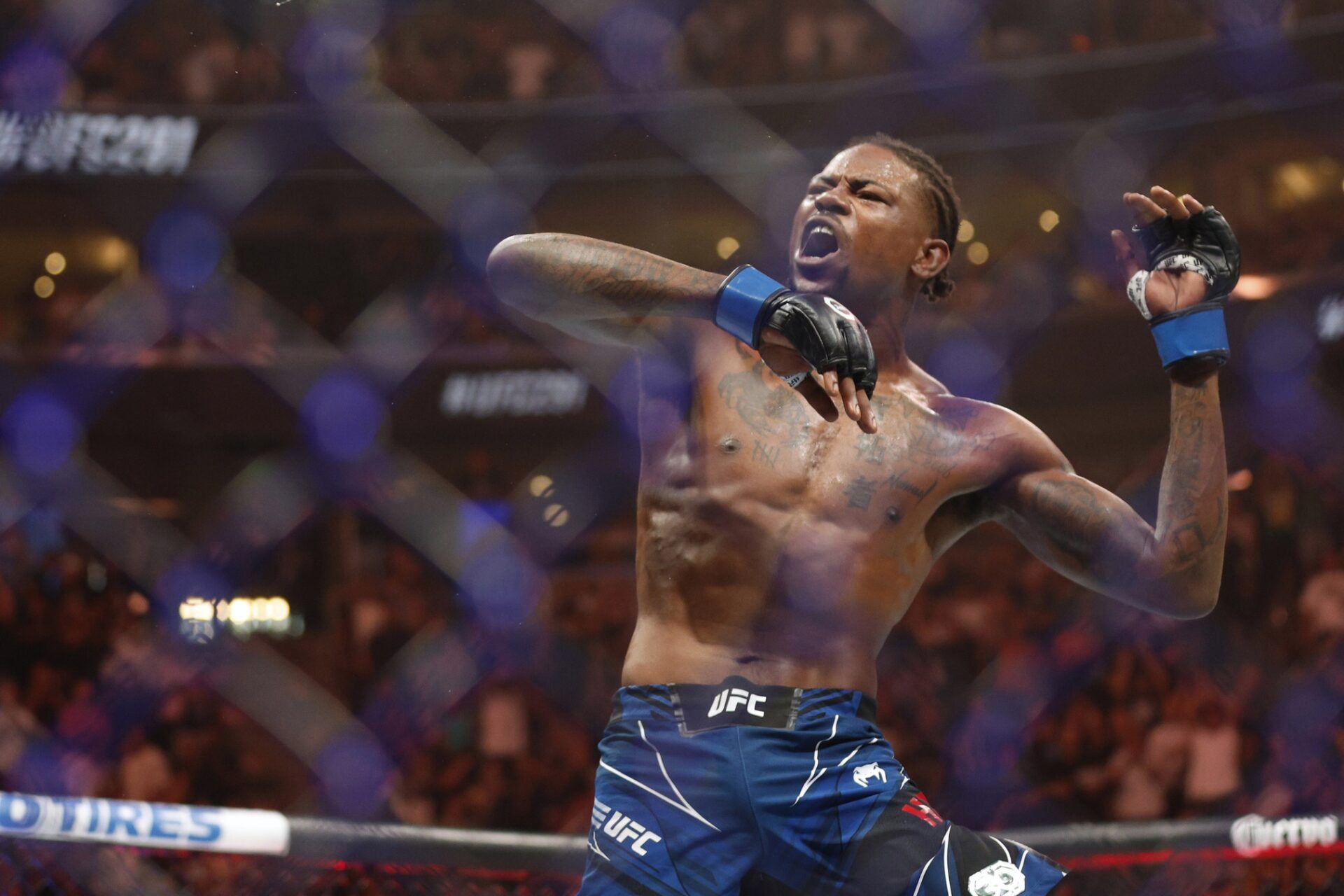 Kevin Holland (blue gloves)  reacts to defeating Michael Chiesa (red gloves) during UFC 291 at Delta Center.