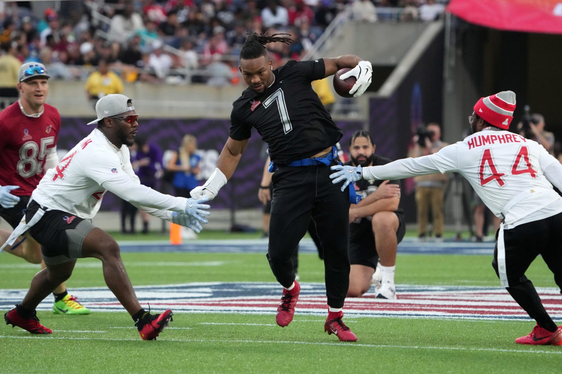 NFC running back Bijan Robinson of the Atlanta Falcons (7) carries the ball against AFC linebacker Zaire Franklin of the Indianapolis Colts (left) and cornerback Marlon Humphrey of the Baltimore Ravens during the 2025 Pro Bowl Games at Camping World Stadium.