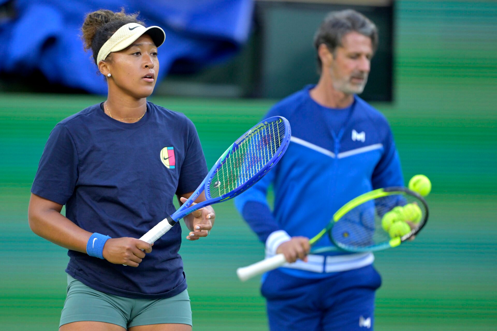 Naomi Osaka (JPN) practices on the first day of the BNP Paribas open as her coach Patrick Mouratoglou looks on at the Indian Well Tennis Garden.