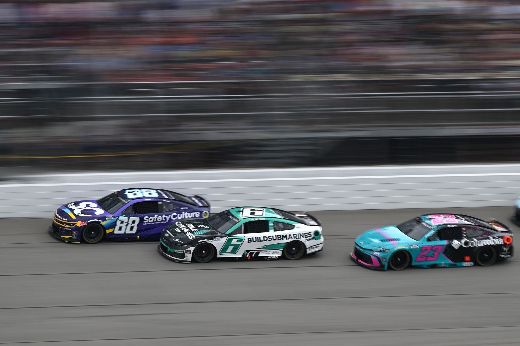 NASCAR Cup Series drivers Shane van Gisbergen (88) Brad Keselowski (6) and driver Bubba Wallace (23) race down the main straightaway during stage three of the FireKeepers Casino 400 at Michigan International Speedway.