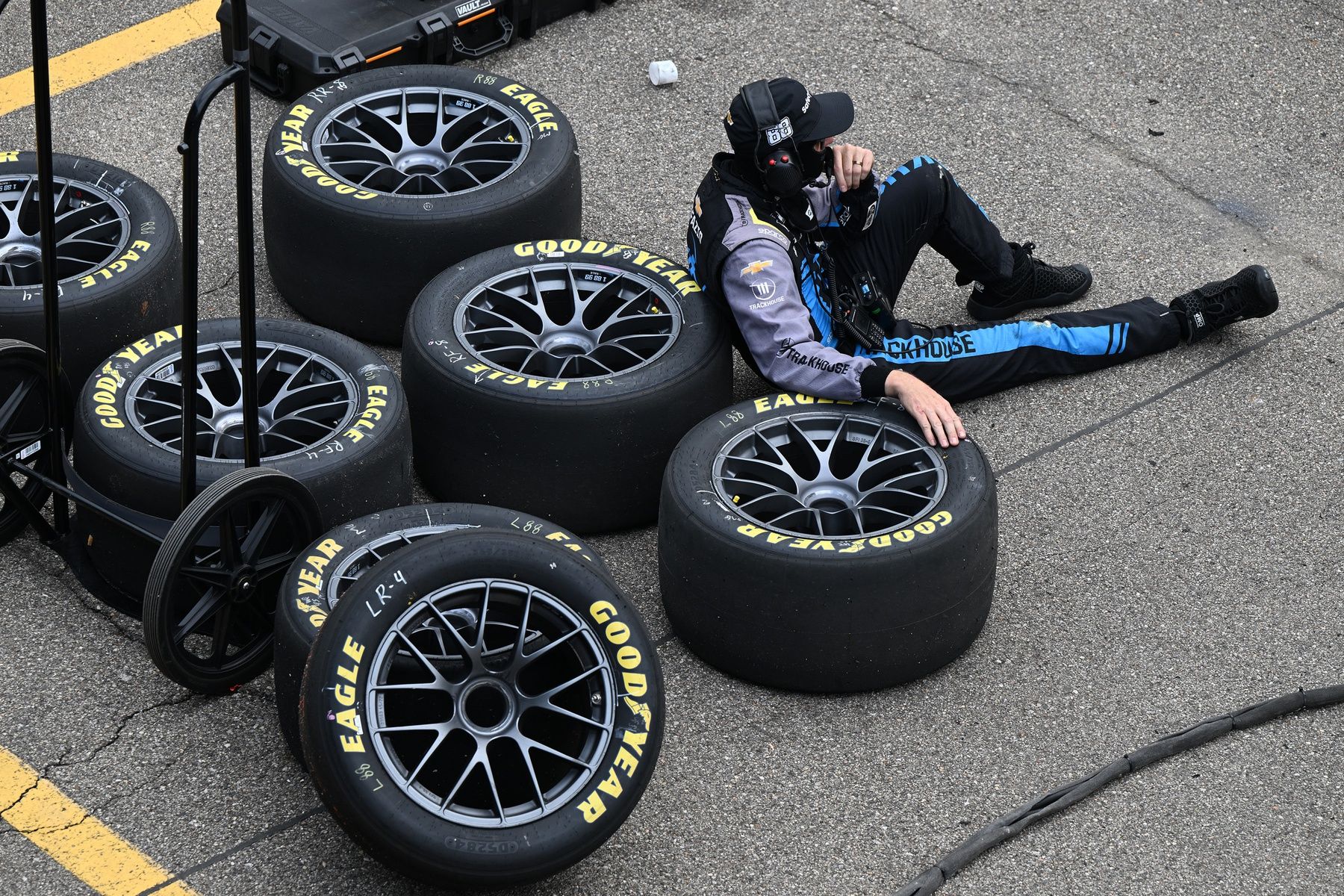 A pit crew member for NASCAR Cup Series driver Shane van Gisbergen (88) rest on a stack of tires after the final pit stop of the day at Michigan International Speedway.