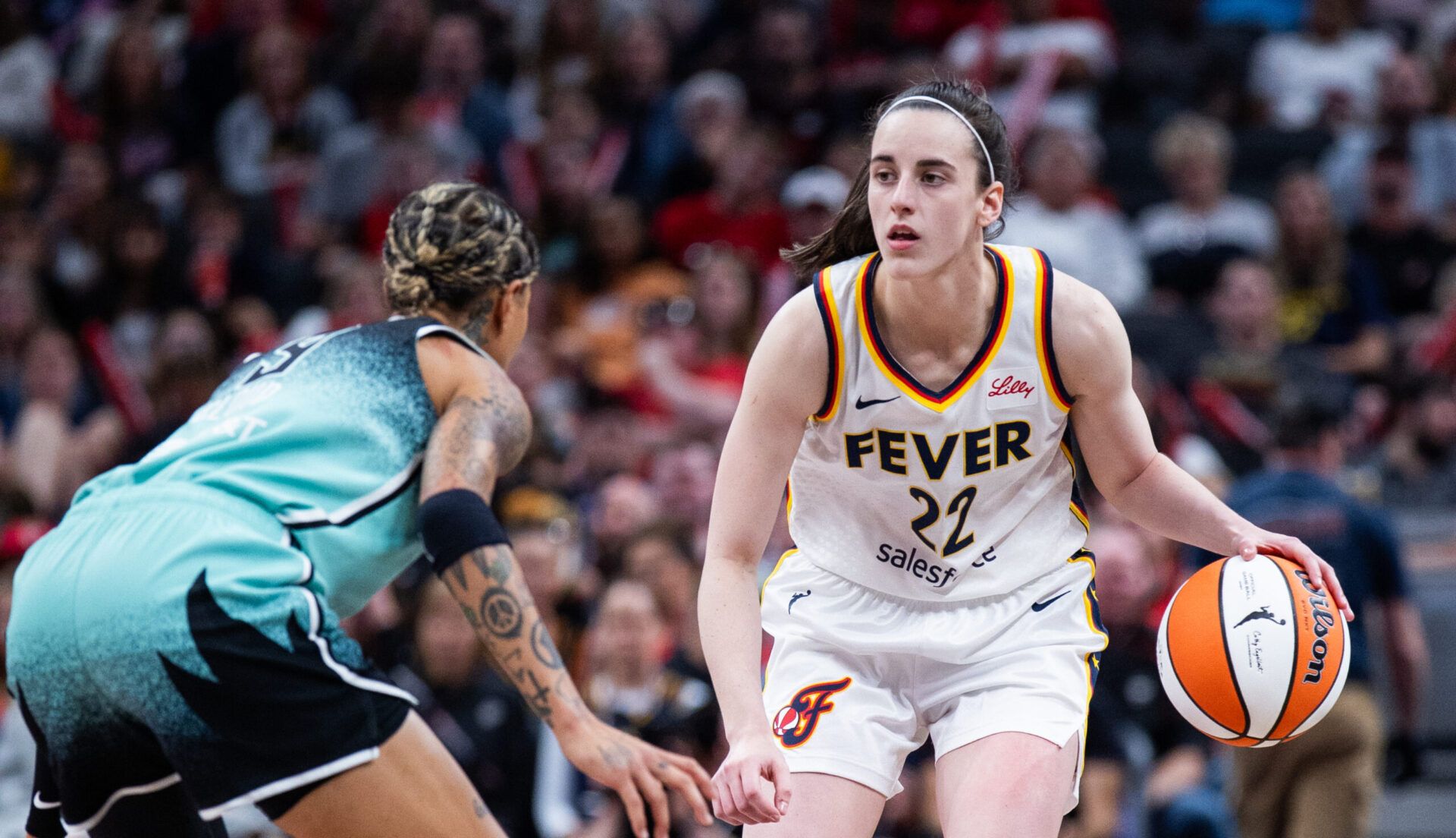 Indiana Fever guard Caitlin Clark (22) dribbles  the ball while New York Liberty guard Natasha Cloud (9) defends in the second half at Gainbridge Fieldhouse.