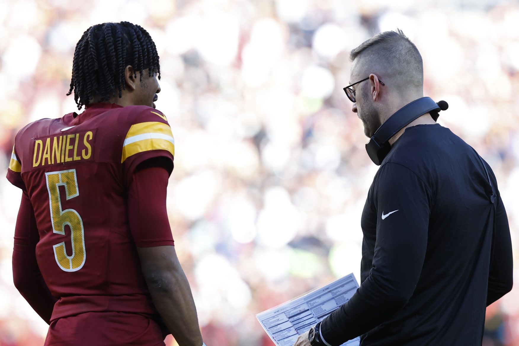 Washington Commanders quarterback Jayden Daniels (5) talks with Commanders offensive coordinator Kliff Kingsbury (R) during a timeout Dallas Cowboys during the second quarter at Northwest Stadium.