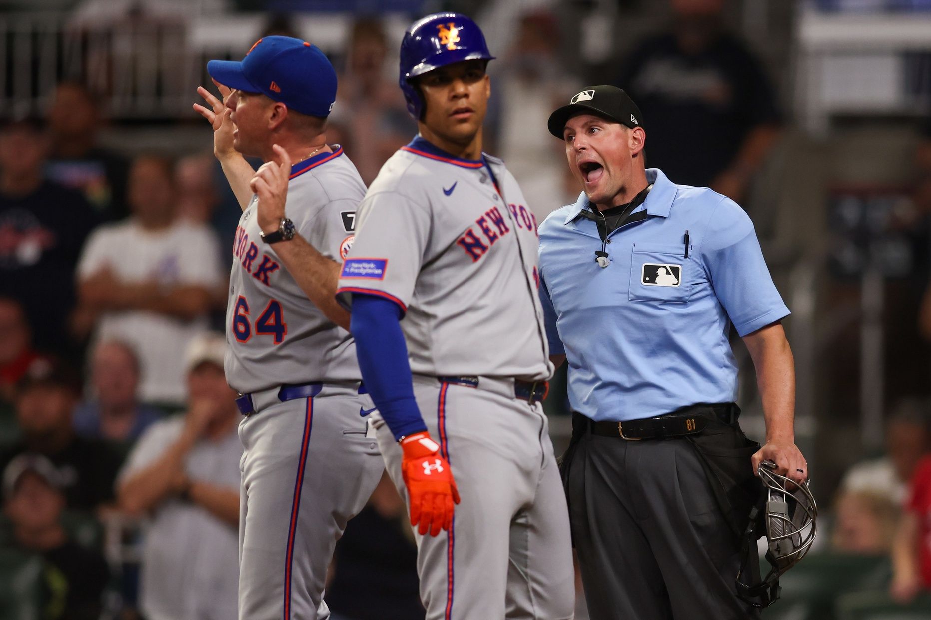 New York Mets right fielder Juan Soto (22) and manager Carlos Mendoza (64) talk to umpire Quinn Wolcott (81) against the Atlanta Braves in the ninth inning at Truist Park.