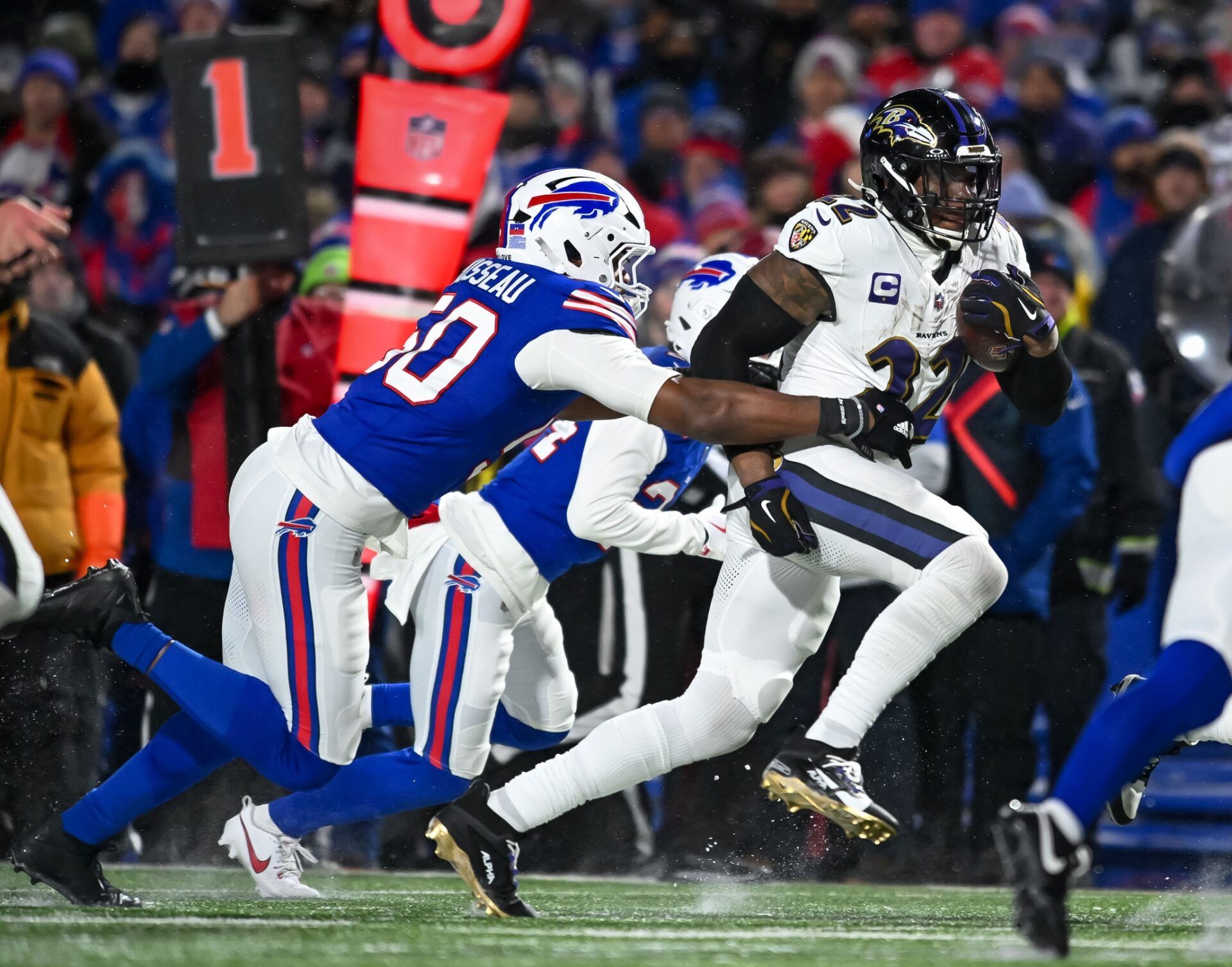 Baltimore Ravens running back Derrick Henry (22) carries the ball as Buffalo Bills defensive end Greg Rousseau (50) attempts a tackle in the third quarter of a 2025 AFC divisional round game at Highmark Stadium.