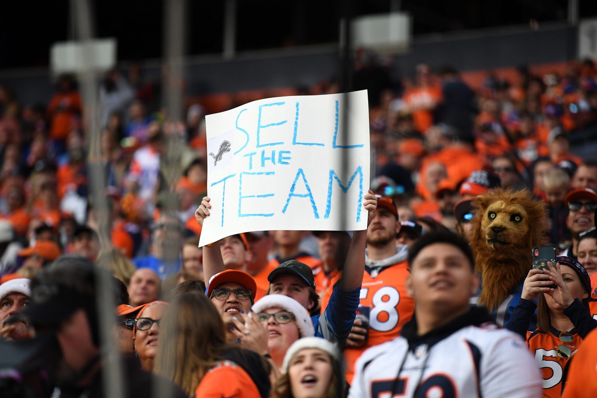 General view as a Detroit Lions fan holds a sign in reference to the sale of the team during the second quarter against the Denver Broncos at Empower Field at Mile High.