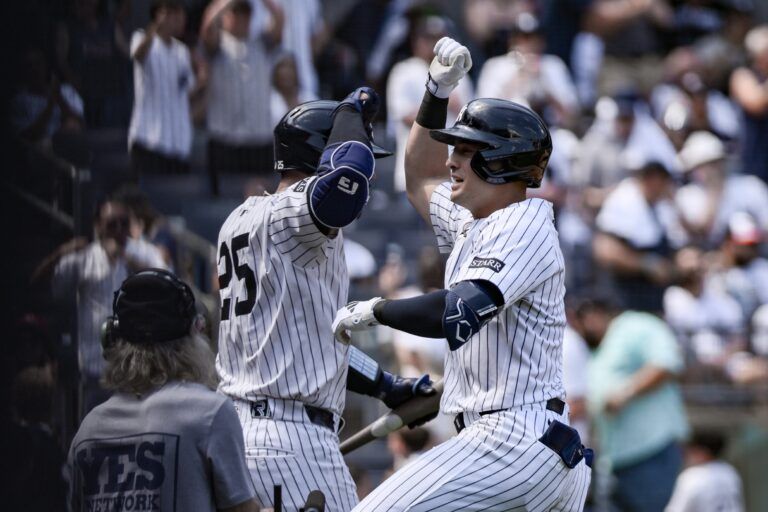 New York Yankees shortstop Anthony Volpe (11) is greeted by catcher J.C. Escarra (25) after hitting a solo home run against the Baltimore Orioles during the fifth inning at Yankee Stadium.