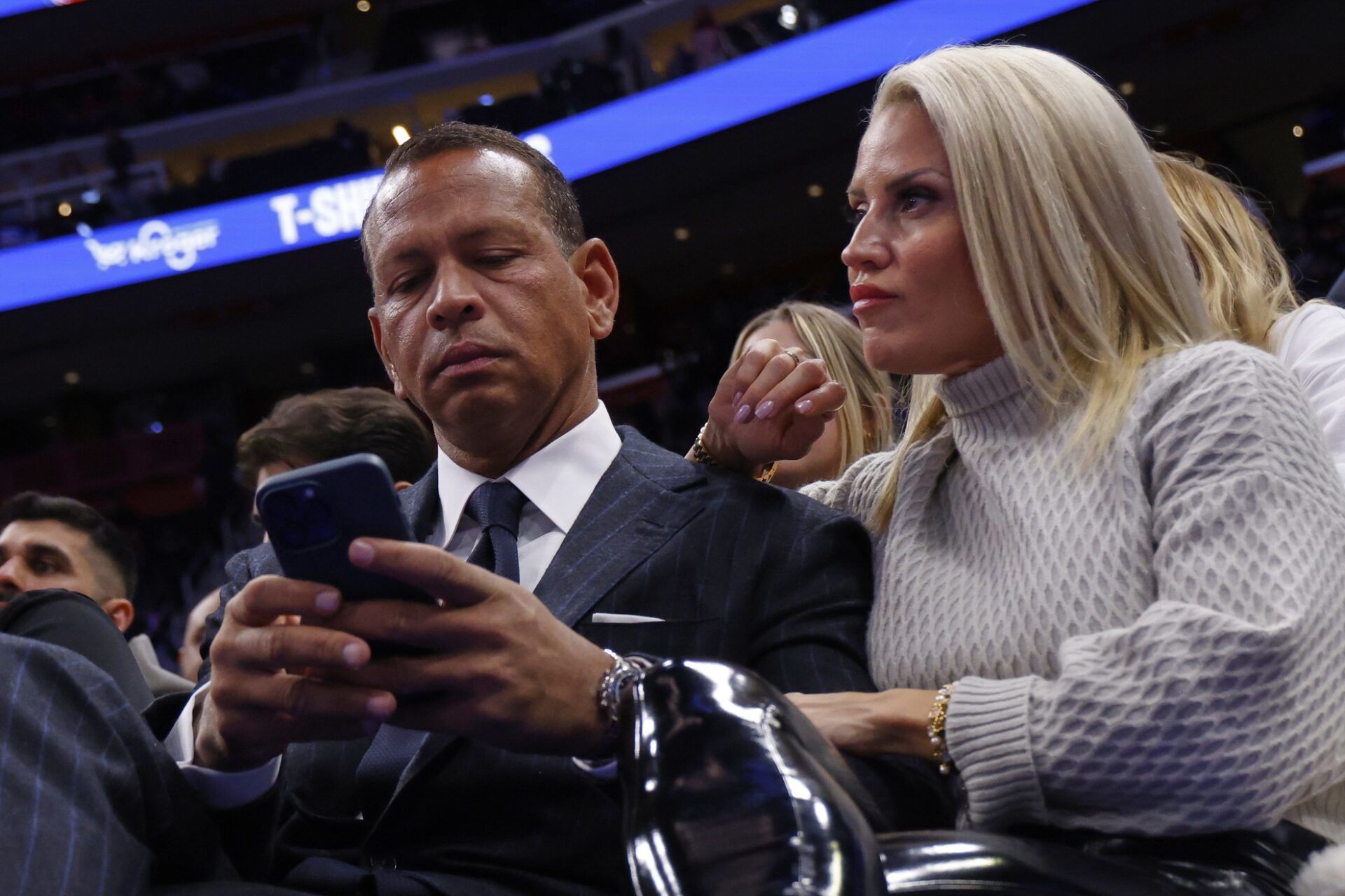 Former New York Yankee and majority owner of Minnesota Timberwolves Alex Rodriguez checks his phone sitting with his girlfriend Canadian fitness instructor Jaclyn Cordeiro during a time out in the second half against the Detroit Pistons at Little Caesars Arena.