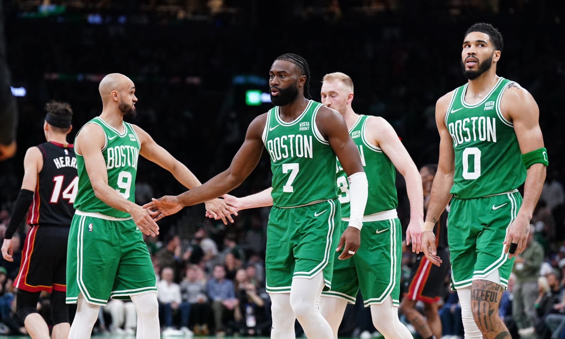 Boston Celtics guard Jaylen Brown (7), forward Jayson Tatum (0), guard Derrick White (9) and forward Sam Hauser (30) walk to the bench during a timeout against the Miami Heat in the second quarter during game two of the first round for the 2024 NBA playoffs at TD Garden.