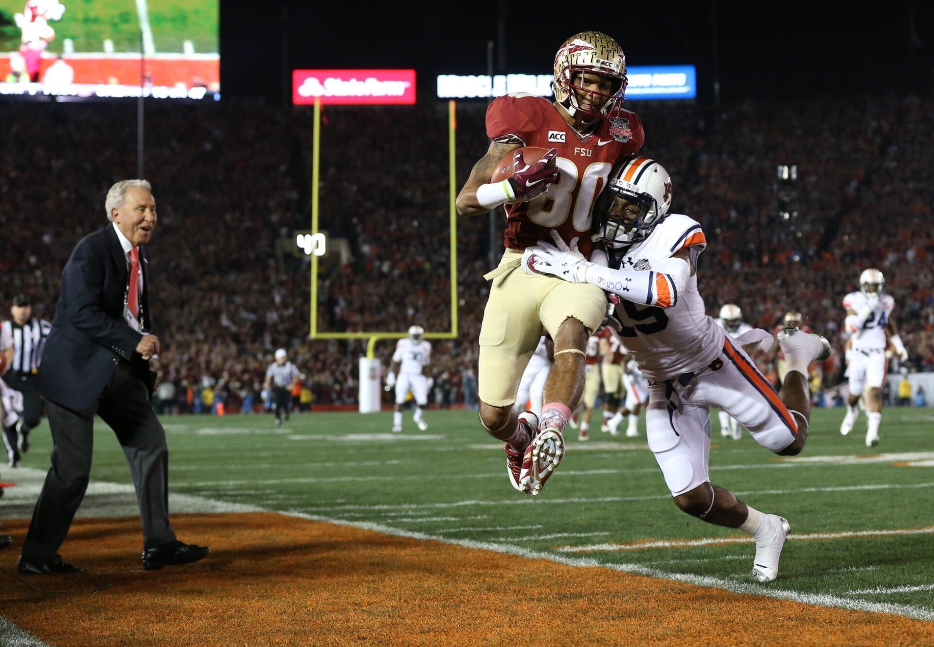 Florida State Seminoles wide receiver Rashad Greene (80) is hit by Auburn Tigers defensive back Ryan White (19) as ESPN analyst Lee Corso (left) looks on from the sideline during the first half of the 2014 BCS National Championship game at the Rose Bowl.