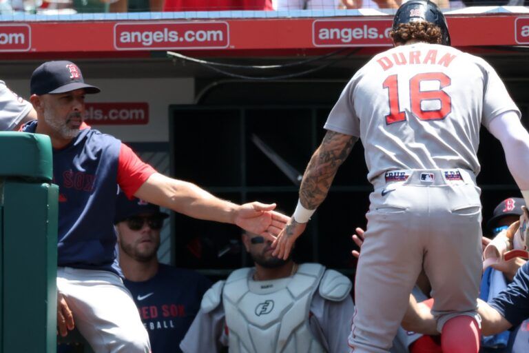 Boston Red Sox left fielder Jarren Duran (16) is greeted by manager Alex Cora (13, left) after scoring a run during the first inning against the Los Angeles Angels at Angel Stadium.