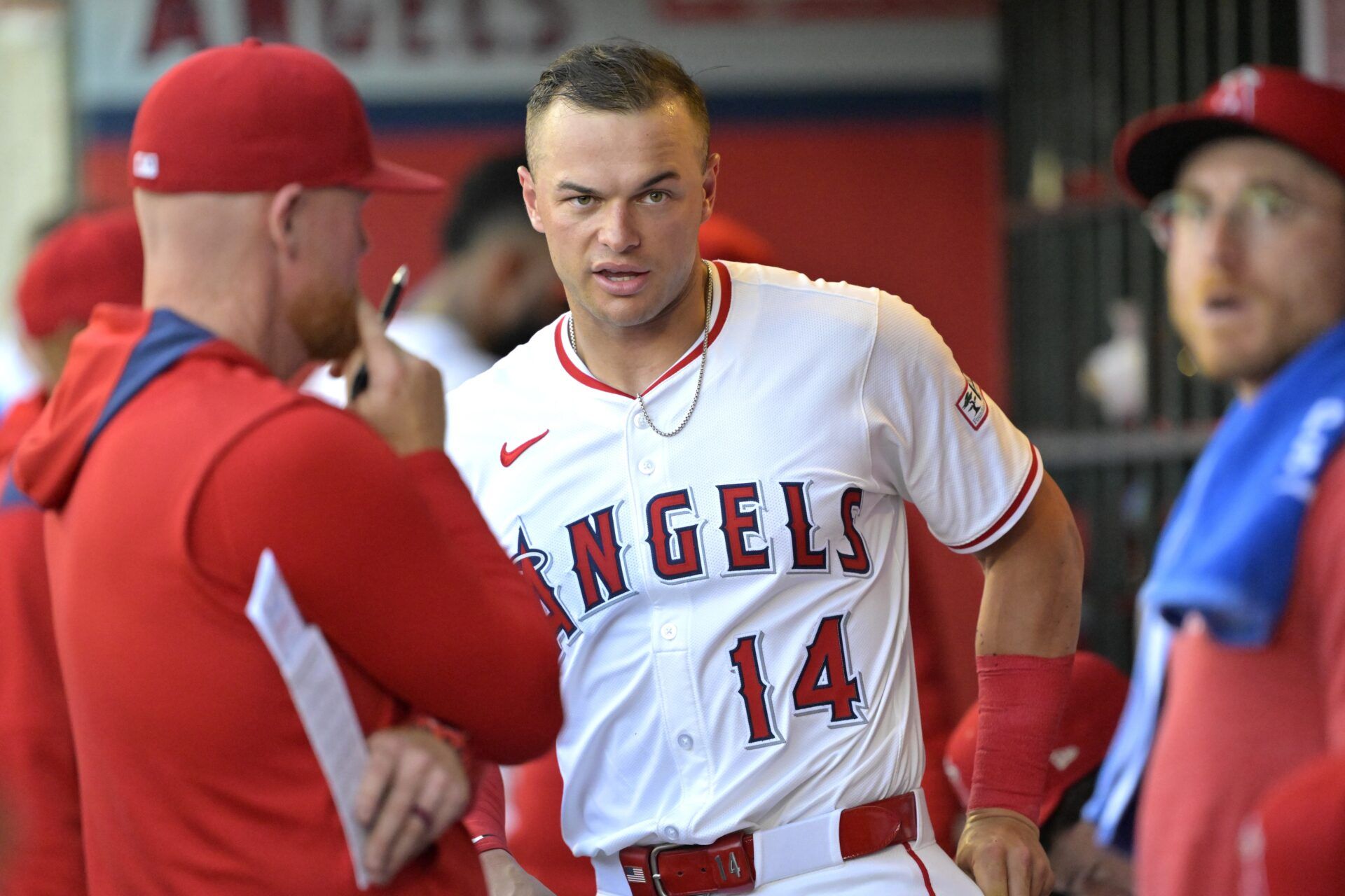 Los Angeles Angels catcher Logan O'Hoppe (14) talks with pitching coach Barry Enright (84) in the dugout during the third inning against the Washington Nationals at Angel Stadium.