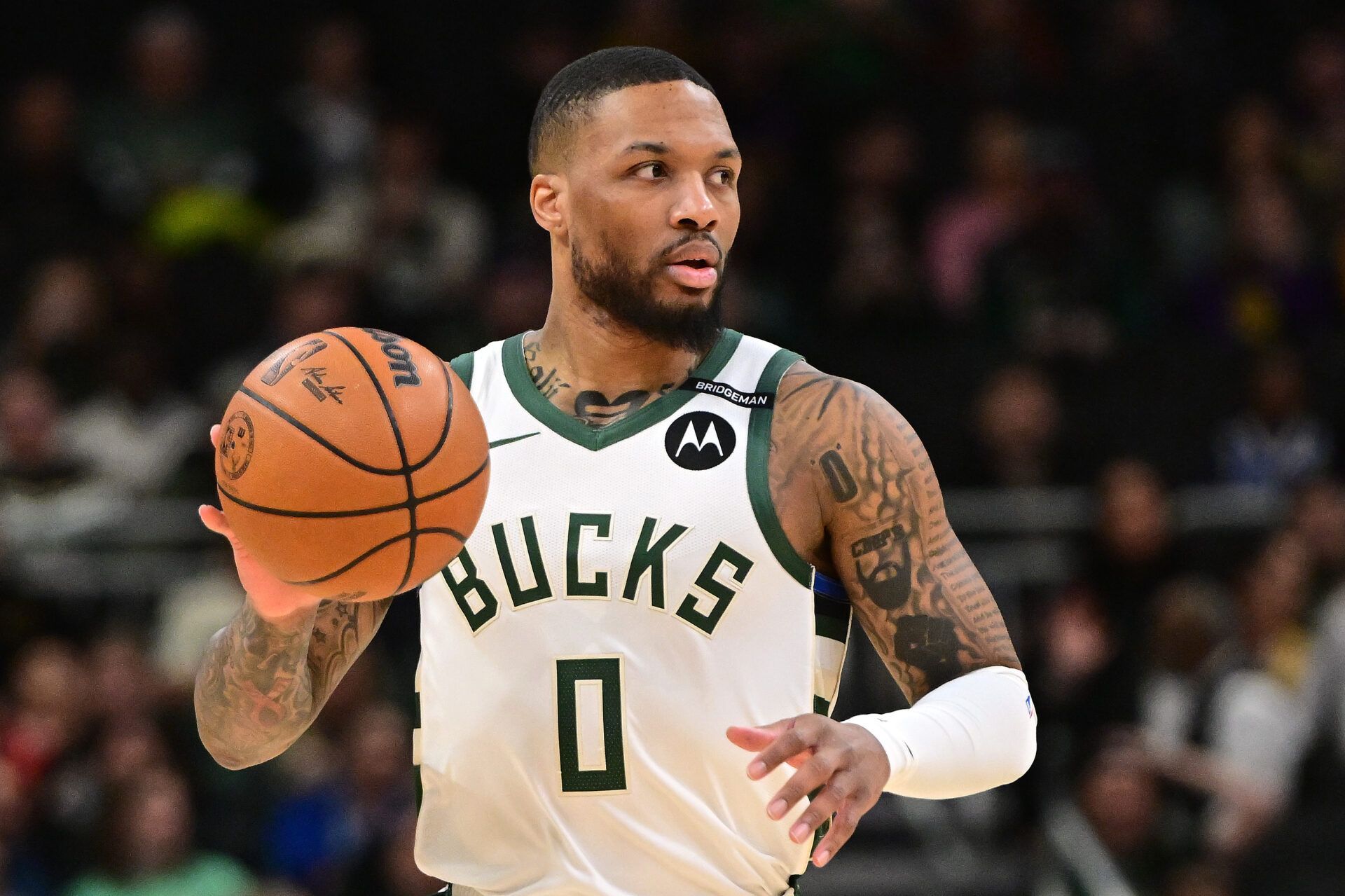 Milwaukee Bucks guard Damian Lillard (0) dribbles the ball against the Los Angeles Lakers in the first quarter at Fiserv Forum. The Bucks wore a small patch to honor former player Junior Bridgeman who passed away this week.