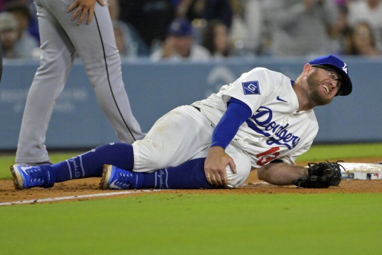 Los Angeles Dodgers third baseman Max Muncy (13) grabs his knee after tagging Chicago White Sox right fielder Michael A. Taylor (21) out on an attempted stolen base during the fifth inning at Dodger Stadium.