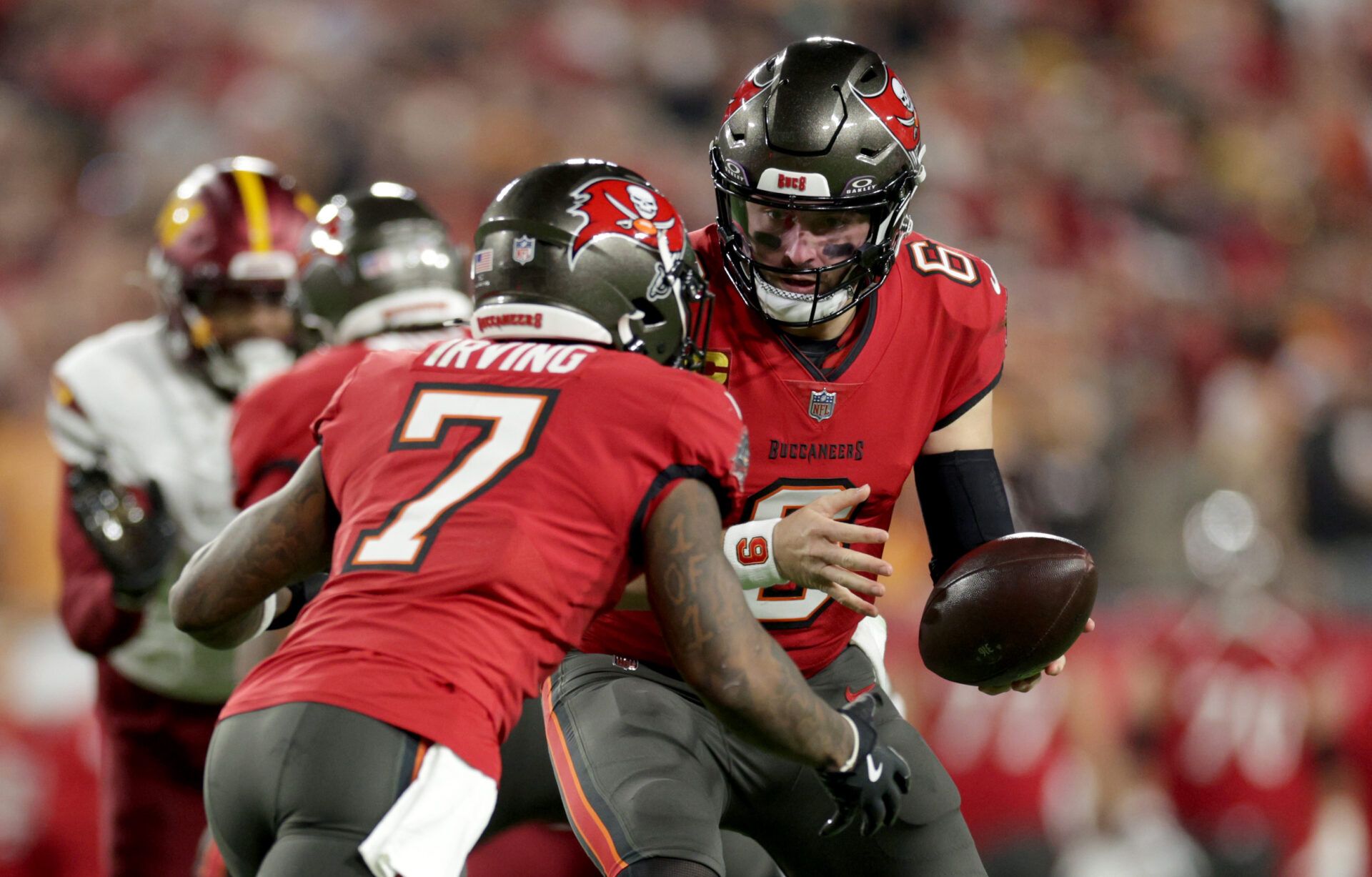 Tampa Bay Buccaneers quarterback Baker Mayfield (6) hands off to running back Bucky Irving (7) during the first quarter of a NFC wild card playoff against the Washington Commanders at Raymond James Stadium.