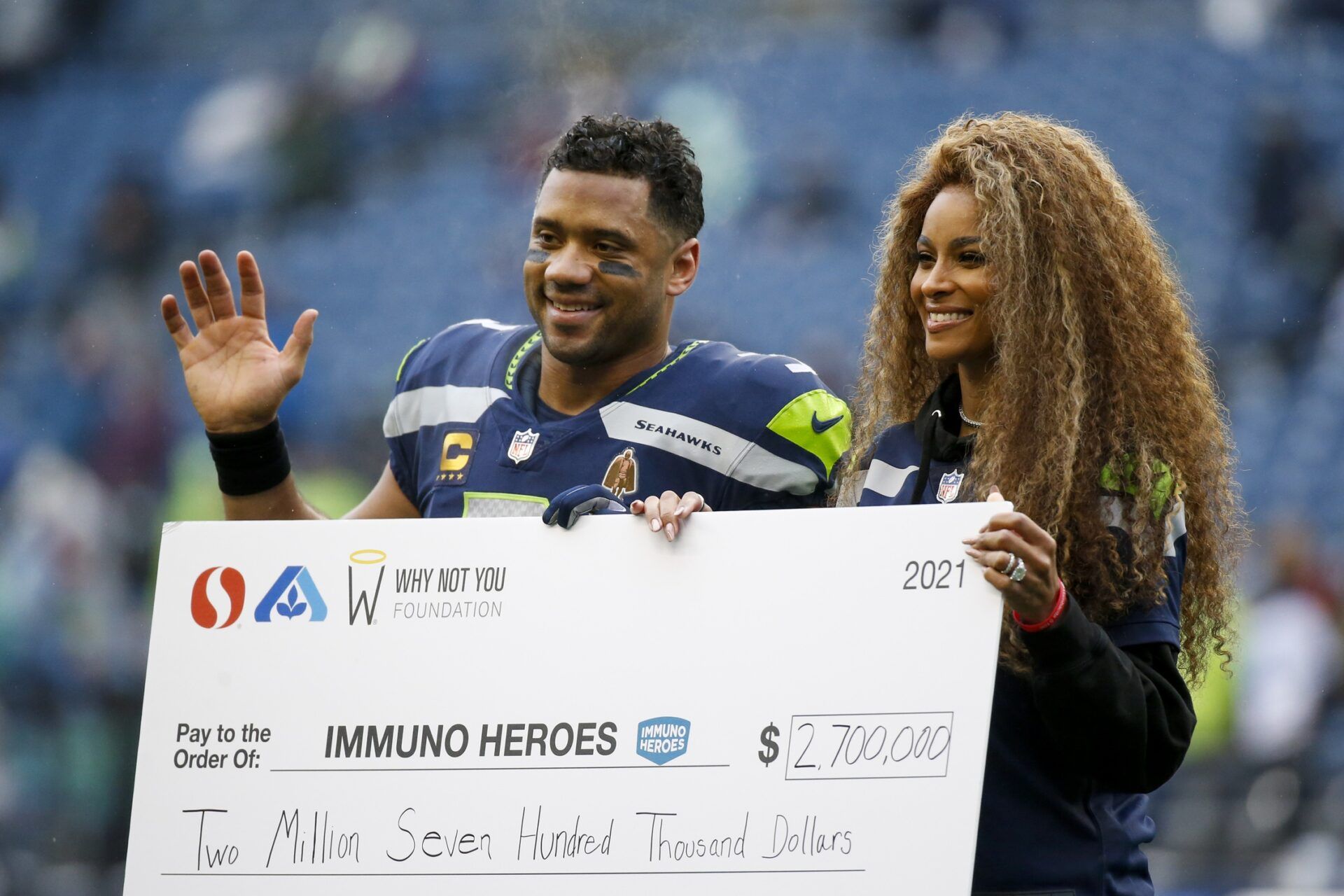 Seattle Seahawks quarterback Russell Wilson (3) and wife Ciara pose for a photo with a charitable donation check during a ceremony before a game against the Detroit Lions at Lumen Field.