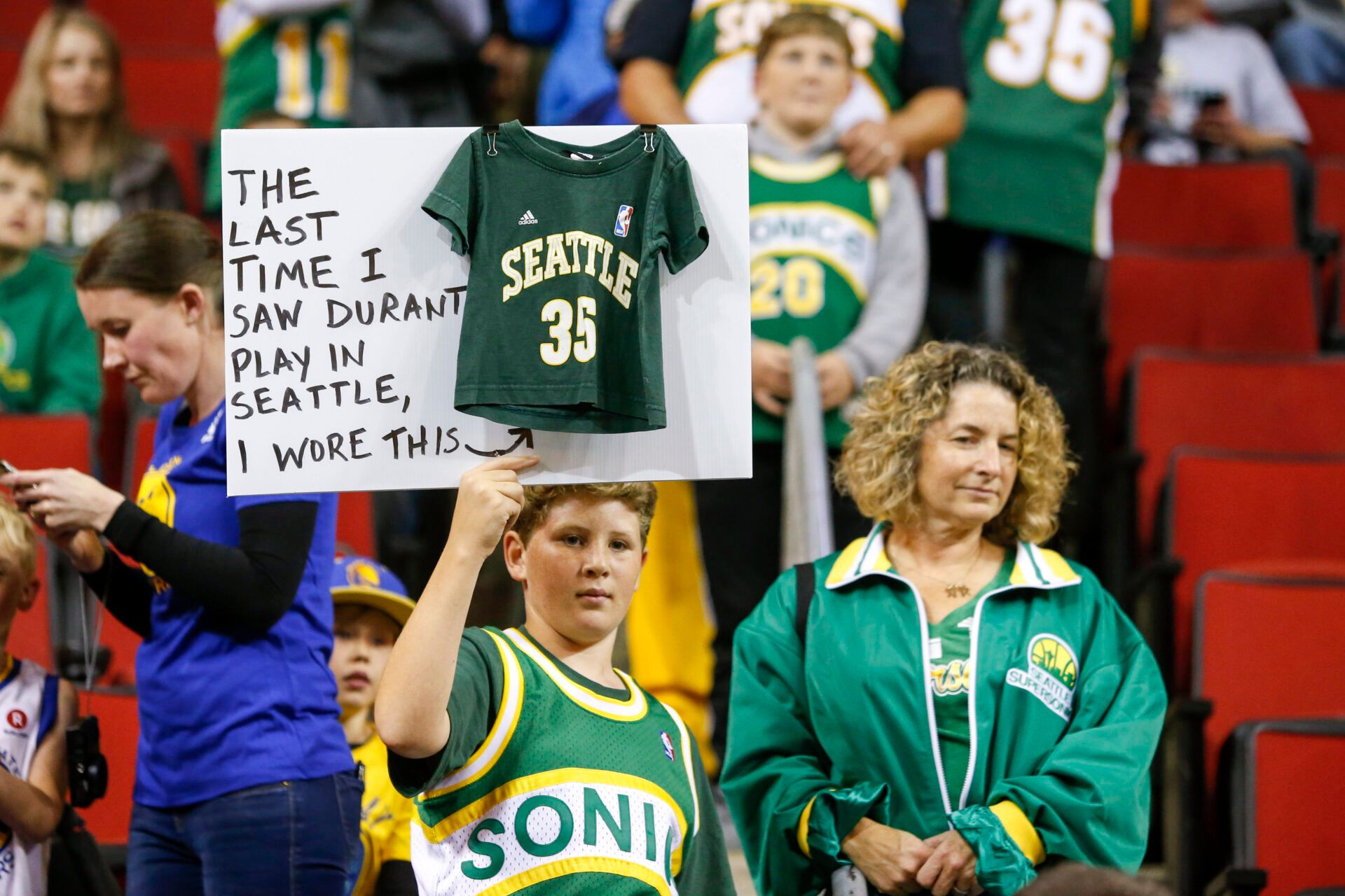 Seattle Supersonics fan Ervin Fleshman of Edison, Washington holds a sign with his mother Allison (right) during pregame warmups for a game between the Golden State Warriors and Sacramento Kings at KeyArena.