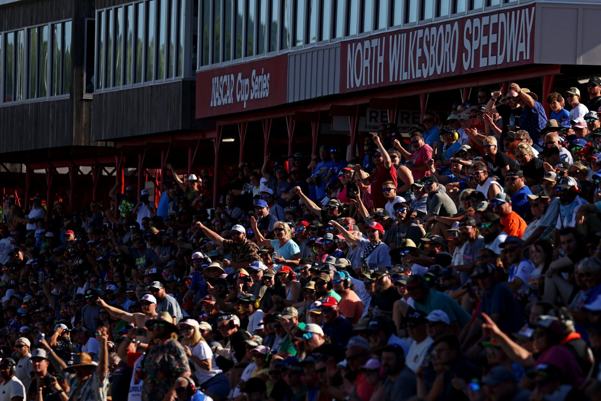 Fans cheer in the grand stands during the heat races for the NASCAR All-Star race at North Wilkesboro Speedway.