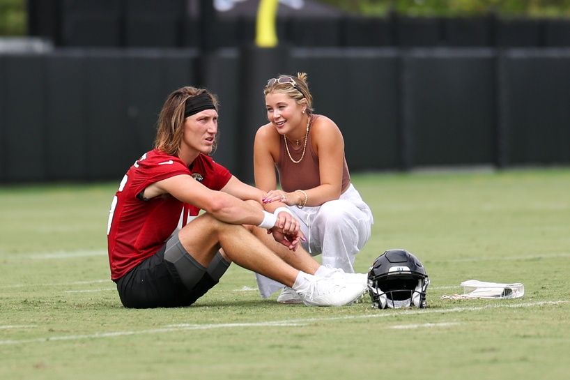 Jacksonville Jaguars quarterback Trevor Lawrence (16) and his wife Marissa sit on the field after training camp at Miller Electric Performance Center.