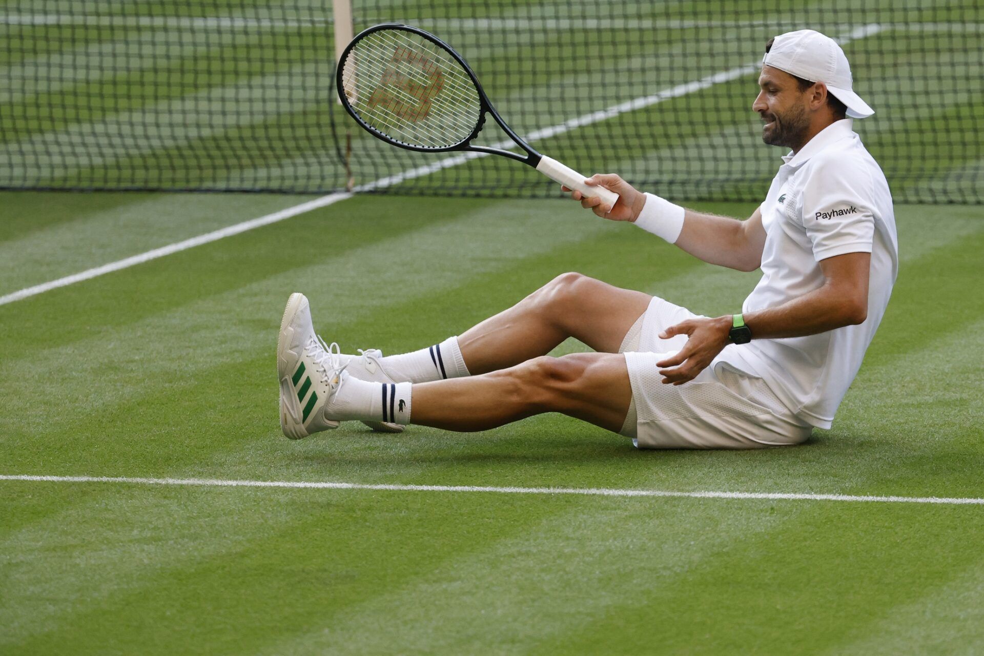 Grigor Dimitrov (BUL) stretches his foot after a fall against Jannik Sinner (ITA)(not pictured) on day eight of The Championships Wimbledon 2025 at All England Lawn Tennis and Croquet Club.