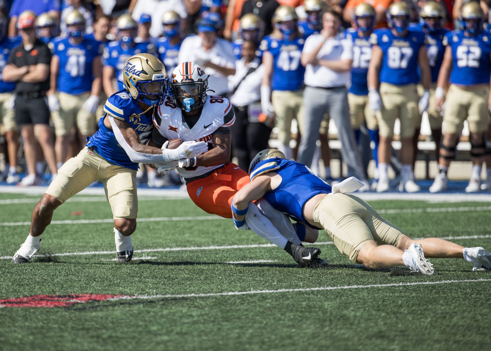 Tulsa Golden Hurricane safety Devin Robinson (16) and safety Dayne Hodge (1) tackle Oklahoma State Cowboys wide receiver Brennan Presley (80) during a game at Skelly Field at H.A. Chapman Stadium.