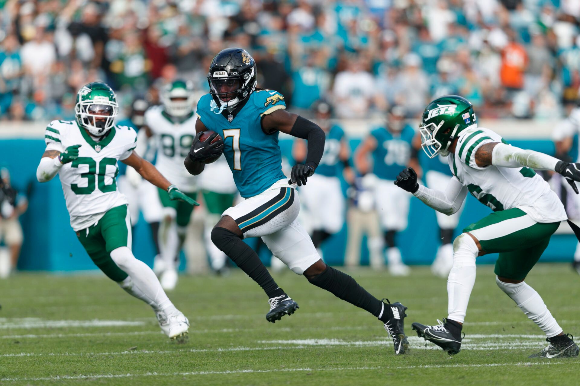 Jacksonville Jaguars wide receiver Brian Thomas Jr. (7) runs through New York Jets cornerback Michael Carter II (30) and safety Chuck Clark (36) during the third quarter at EverBank Stadium.