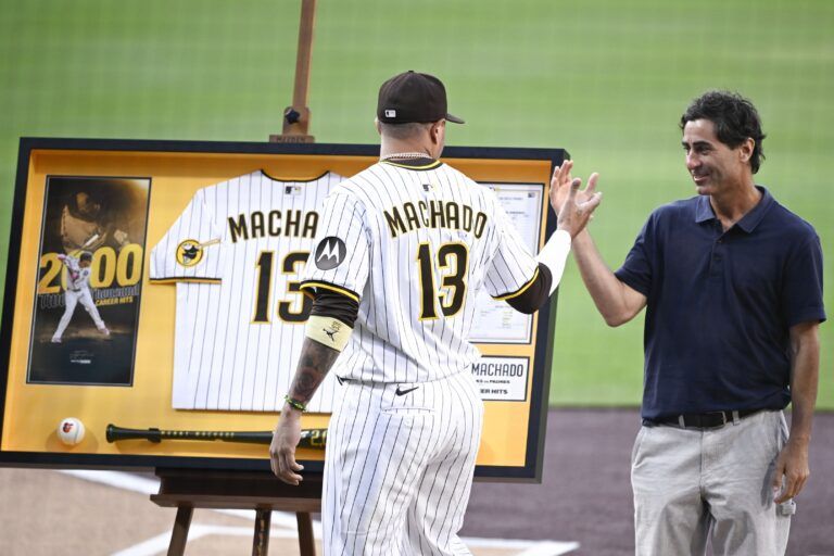 San Diego Padres third baseman Manny Machado (13) shakes hands with general manager A.J. Preller after receiving commemorative memorabilia recognizing his 2,000th hit before a baseball game against the Arizona Diamondbacks at Petco Park.