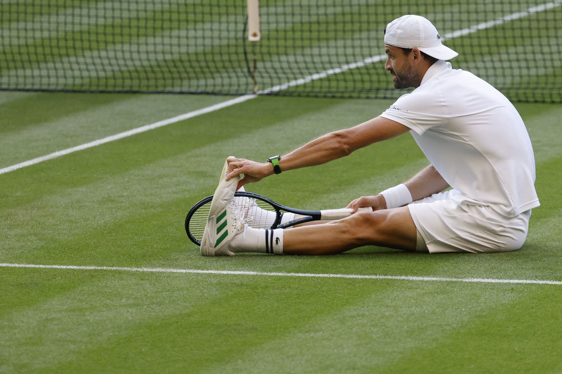 Grigor Dimitrov (BUL) stretches his foot after a fall against Jannik Sinner (ITA)(not pictured) on day eight of The Championships Wimbledon 2025 at All England Lawn Tennis and Croquet Club.