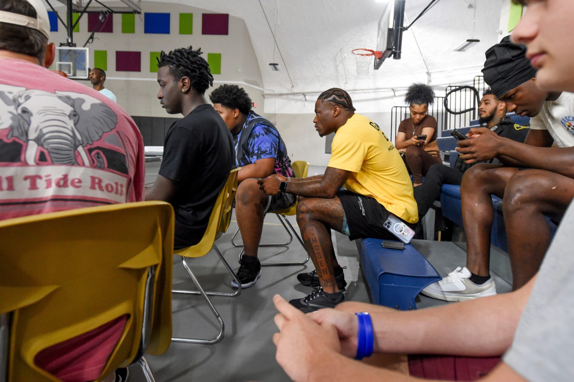 Alabama quarterback Jalen Milroe, center in yellow, hunches of the game controller as he plays the new EA Sports College Football 25 video game at the McDonald Hughes Center in Tuscaloosa with young people Saturday, July 20, 2024.