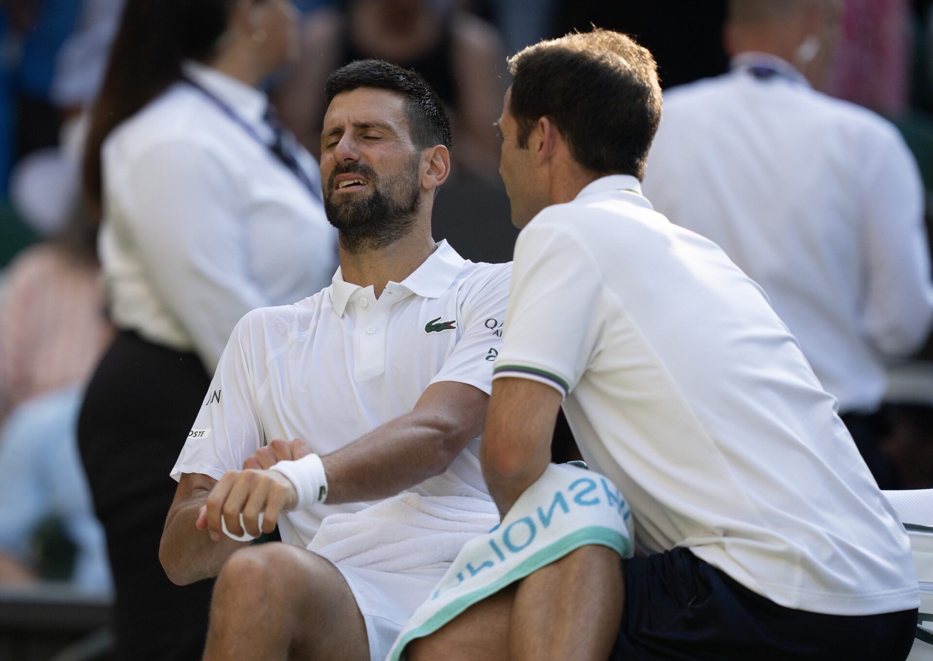 Novak Djokovic of Serbia receives a medical time out during his match to Jannik Sinner of Italy after their match on day 12 at All England Lawn Tennis and Croquet Club.