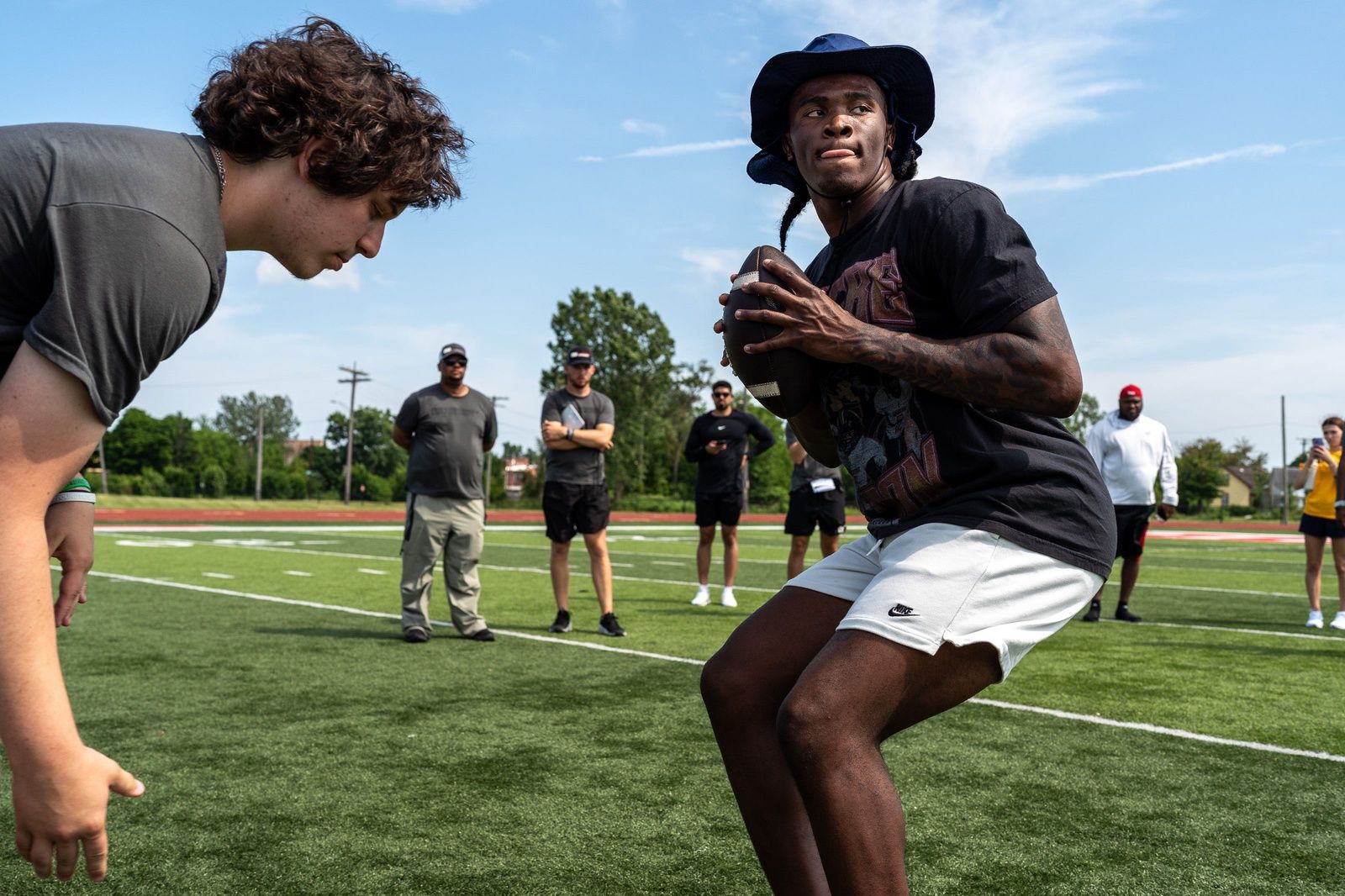 Josh Putman, 19, a member of Quarterback University, snaps the ball to Bryce Underwood, 17, a freshman quarterback at Michigan, during a private workout in Detroit on Saturday, June 21, 2025.