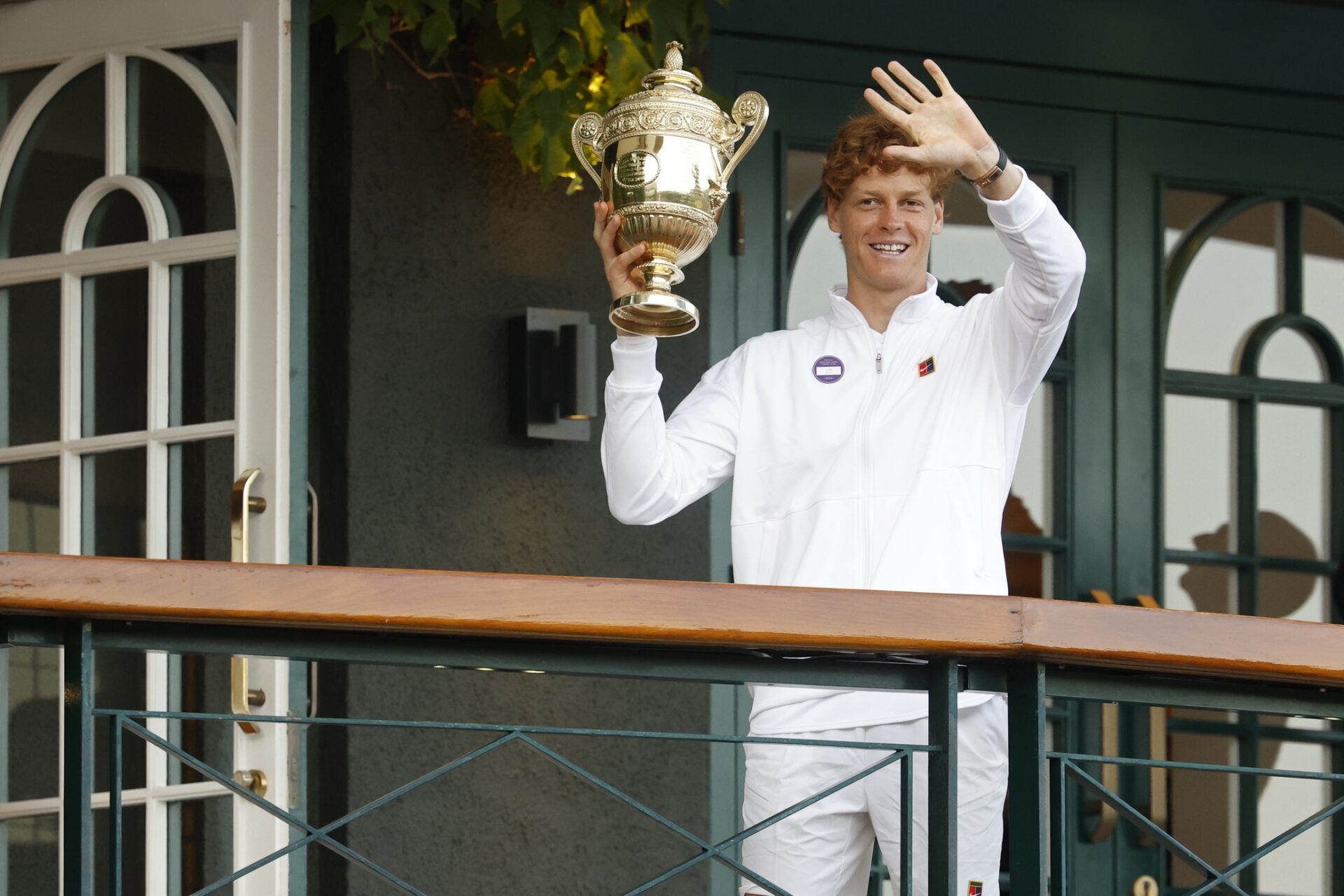 Jannik Sinner (ITA) waves to fans while standing on the South West Hall balcony holding the gentlemen's singles champion trophy, after his match against Carlos Alcaraz (ESP)(not pictured) in the gentlemen's' singles final of The Championships Wimbledon 2025 at All England Lawn Tennis and Croquet Club.