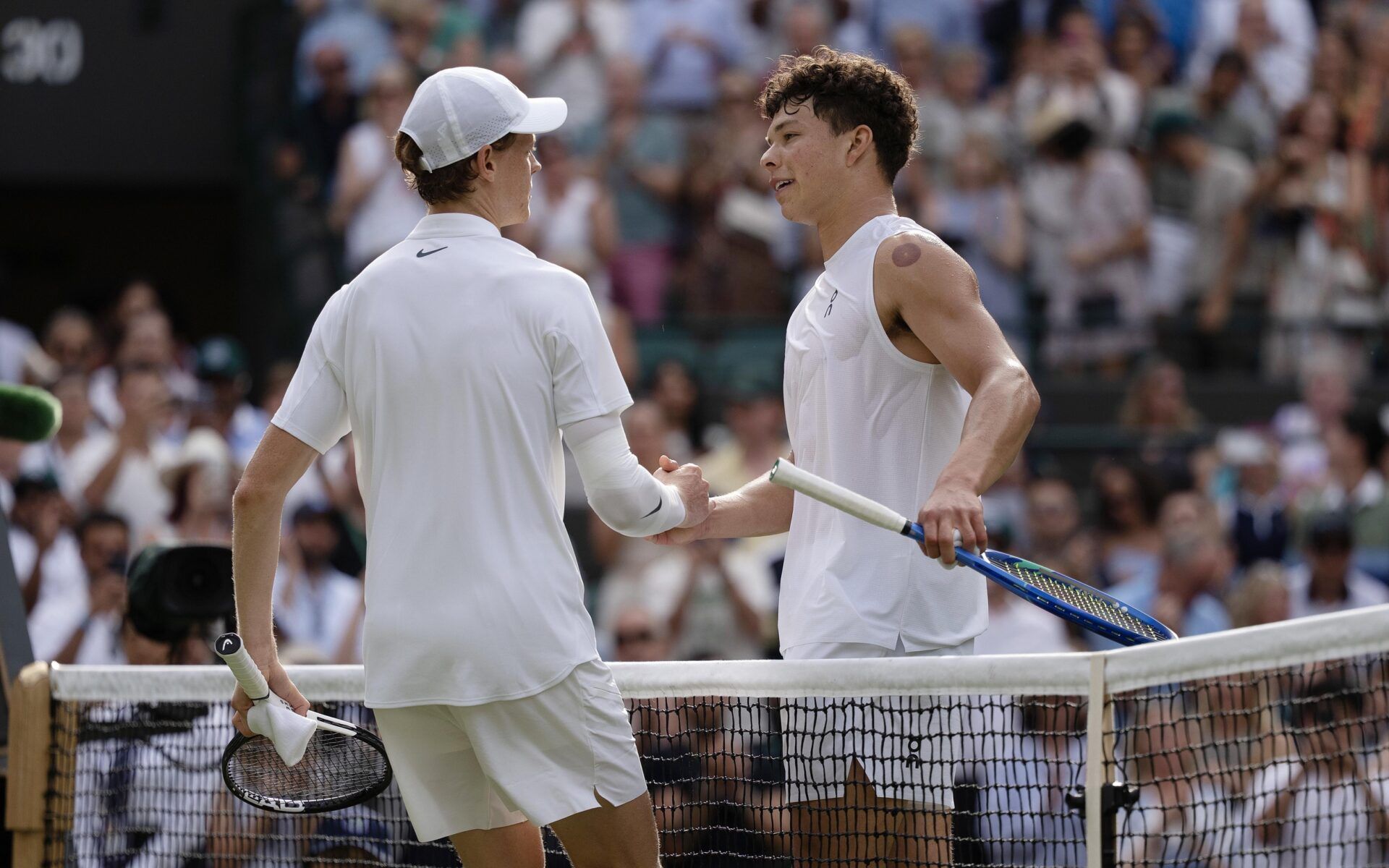 Jannik Sinner of Italy at the net with Ben Shelton of the United States after their match on day 10 at All England Lawn Tennis and Croquet Club.