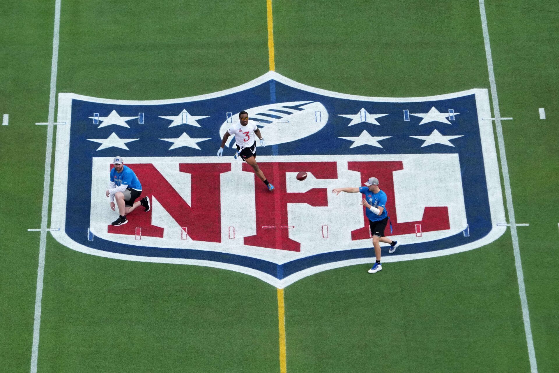 A general overall view as NFC quarterback Jared Goff of the Detroit Lions (16) throws the ball on the NFL shield logo at midfield under pressure from AFC safety Derwin James of the Los Angeles Chargers (3) during the 2025 Pro Bowl Games at Camping World Stadium.