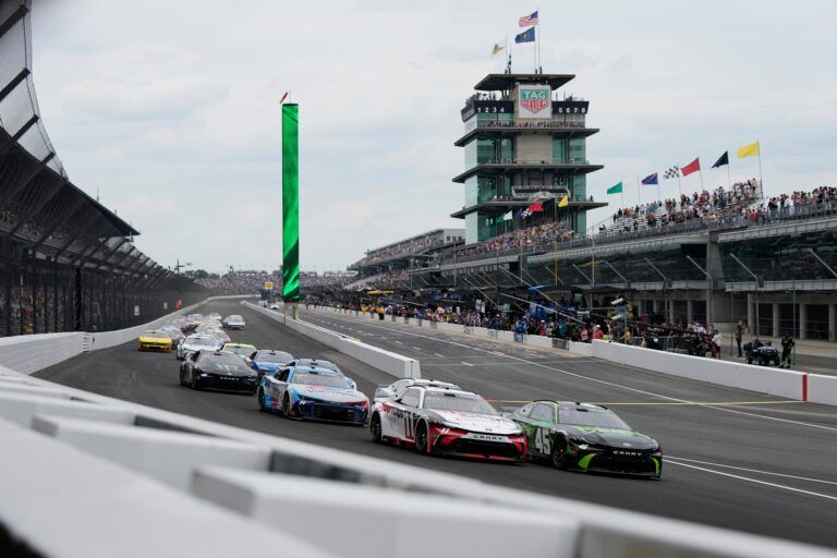 NASCAR Cup Series drivers Tyler Reddick (45) and Denny Hamlin (11) lead the field around the first turn after taking the green flag on Sunday, July 21, 2024, during the Brickyard 400 at Indianapolis Motor Speedway.