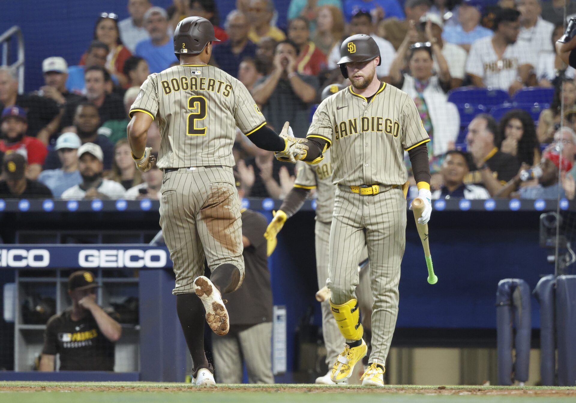 San Diego Padres shortstop Xander Bogaerts (2) is greeted at the dugout by San Diego Padres center fielder Jackson Merrill (3) after scoring against the Miami Marlins during the second inning at loanDepot Park.