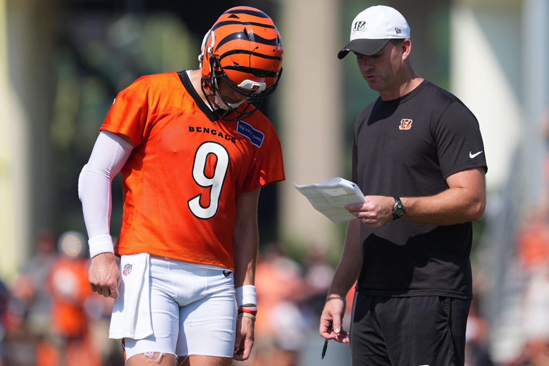 Cincinnati Bengals quarterback Joe Burrow (9), left, talks with head coach Zac Taylor, right, during training camp practice.