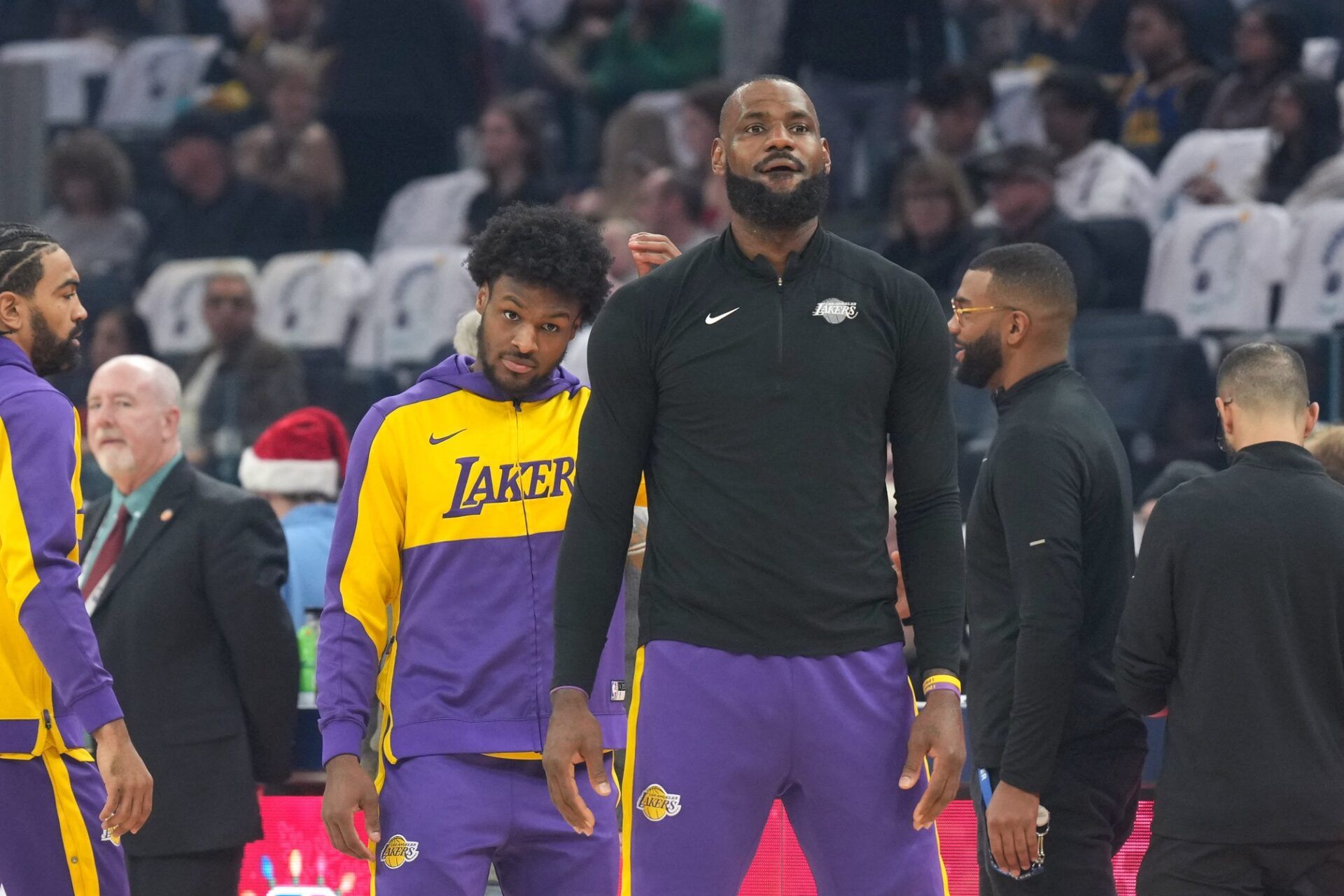 Los Angeles Lakers guard Bronny James (center left) and forward LeBron James (center right) stand on the court before the game against the Golden State Warriors at Chase Center.