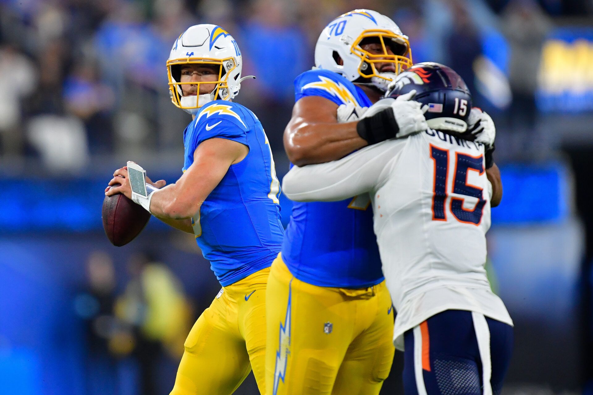 Los Angeles Chargers quarterback Justin Herbert (10) drops back to pass as offensive tackle Rashawn Slater (70) provides coverage against Denver Broncos linebacker Nik Bonitto (15) during the second half at SoFi Stadium.