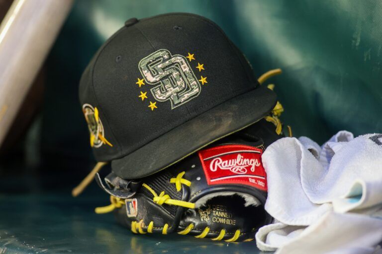 A detailed view of a San Diego Padres hat and glove on the bench against the Atlanta Braves in the third inning at Truist Park.