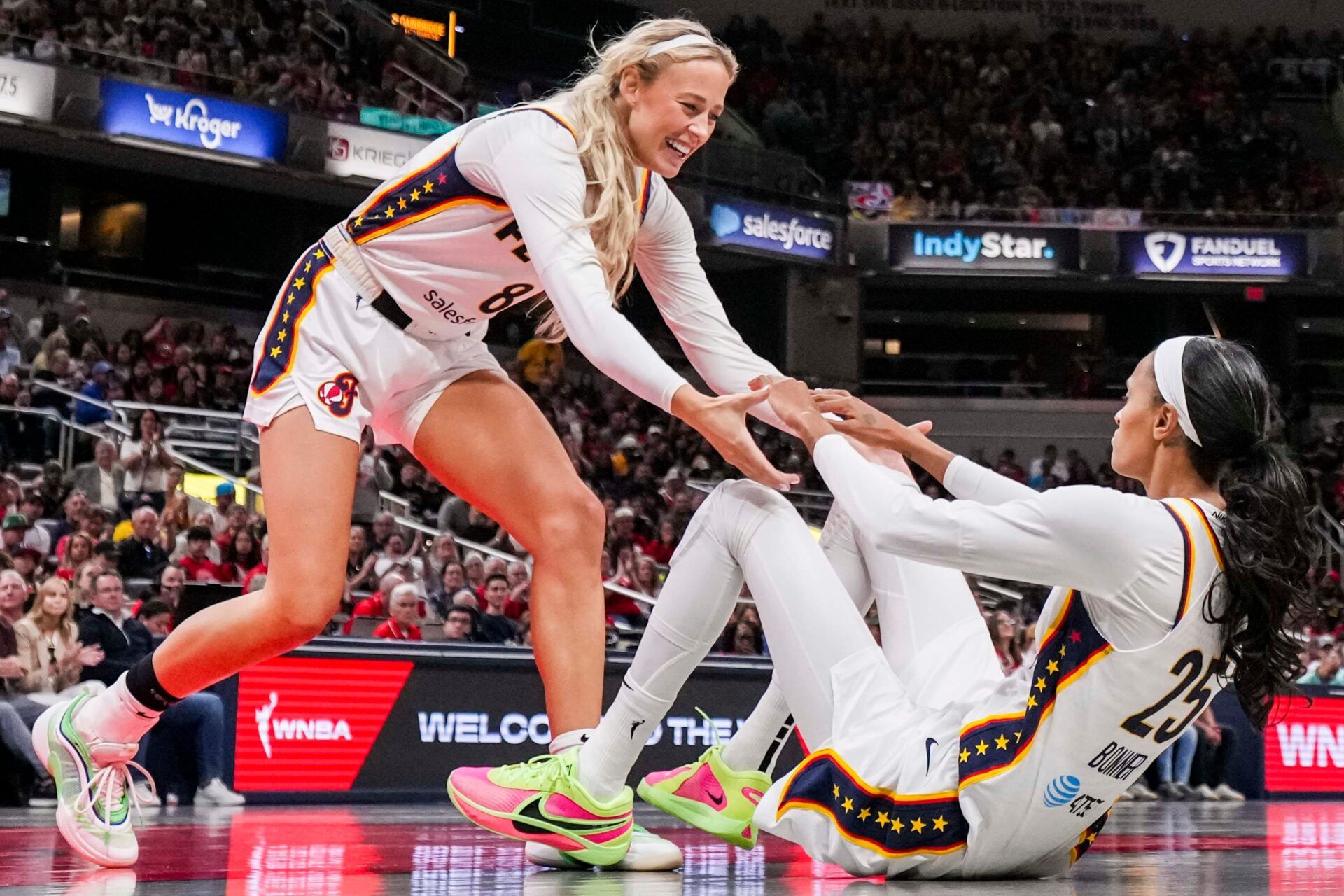 Indiana Fever guard Sophie Cunningham (8) helps Indiana Fever forward DeWanna Bonner (25) up from the ground Saturday, May 24, 2025, during a game between the Indiana Fever and the New York Liberty at Gainbridge Fieldhouse in Indianapolis.