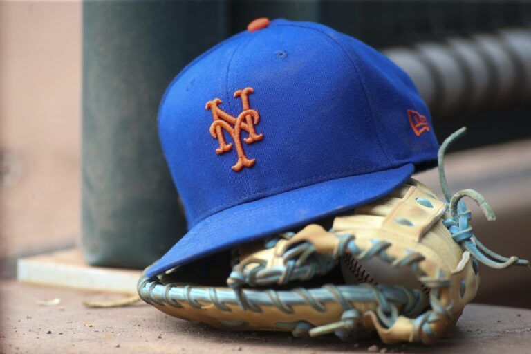 A detailed view of a New York Mets hat and glove in the dugout against the Atlanta Braves in the eighth inning at Truist Park.