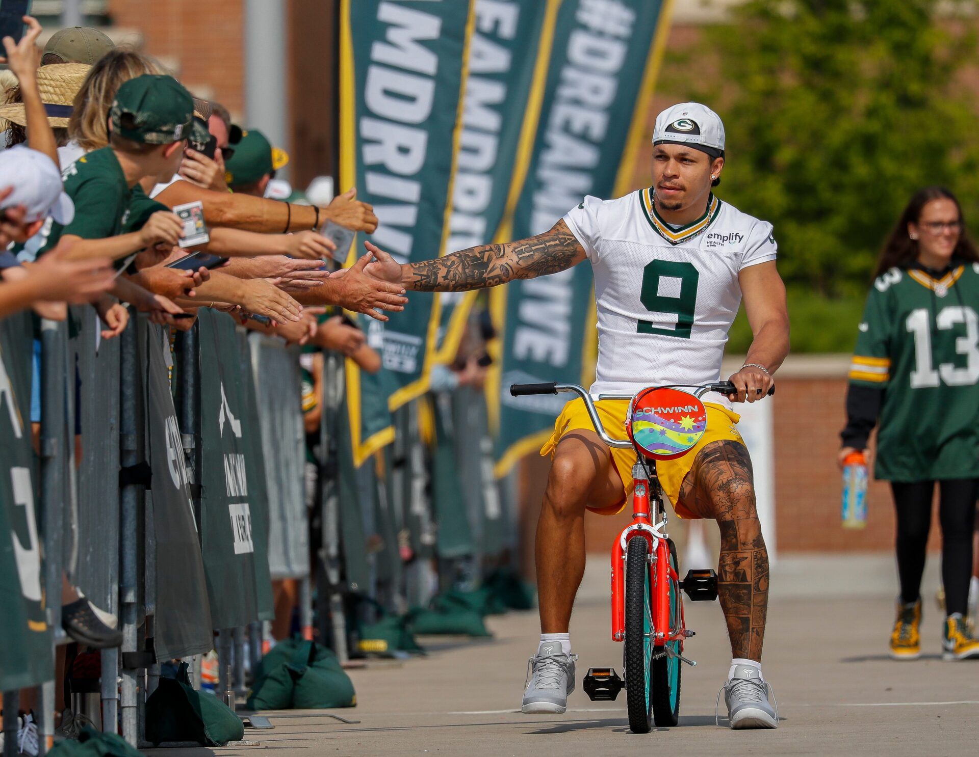 Green Bay Packers wide receiver Christian Watson (9) slaps hands with fans as he rides a bicycle to practice on Wednesday, August 6, 2025, at Lambeau Field in Green Bay, Wis. 
Tork Mason/USA TODAY NETWORK-Wisconsin