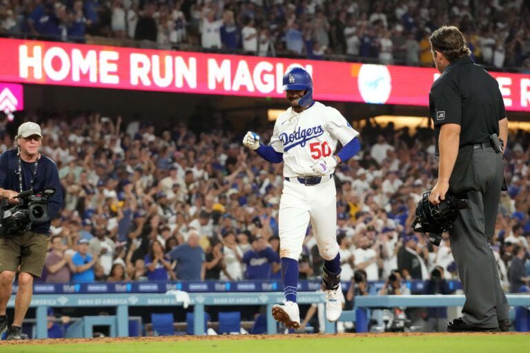 Los Angeles Dodgers shortstop Mookie Betts (50) crosses home plate after hitting a home run in the fifth inning as home plate umpire John Libka (84)  watches against the Toronto Blue Jays at Dodger Stadium.